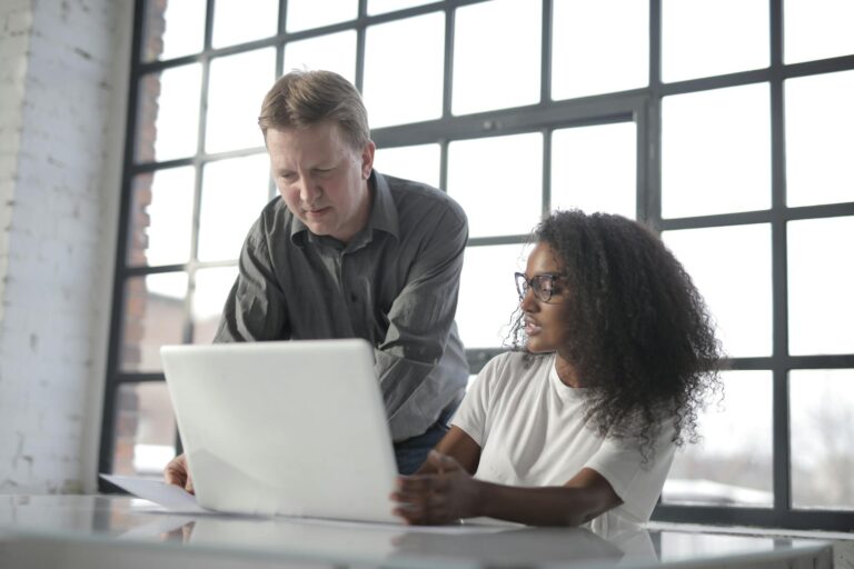 Concentrated diverse coworkers of different age with laptop and documents during office work